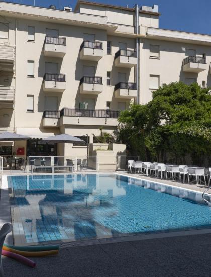 Piscina scintillante accanto a un edificio moderno, atmosfera rilassante e soleggiata.