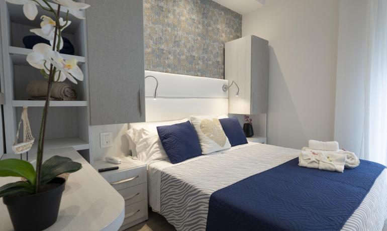 Chambre accueillante avec lit élégant, coussins bleus et décorations florales.